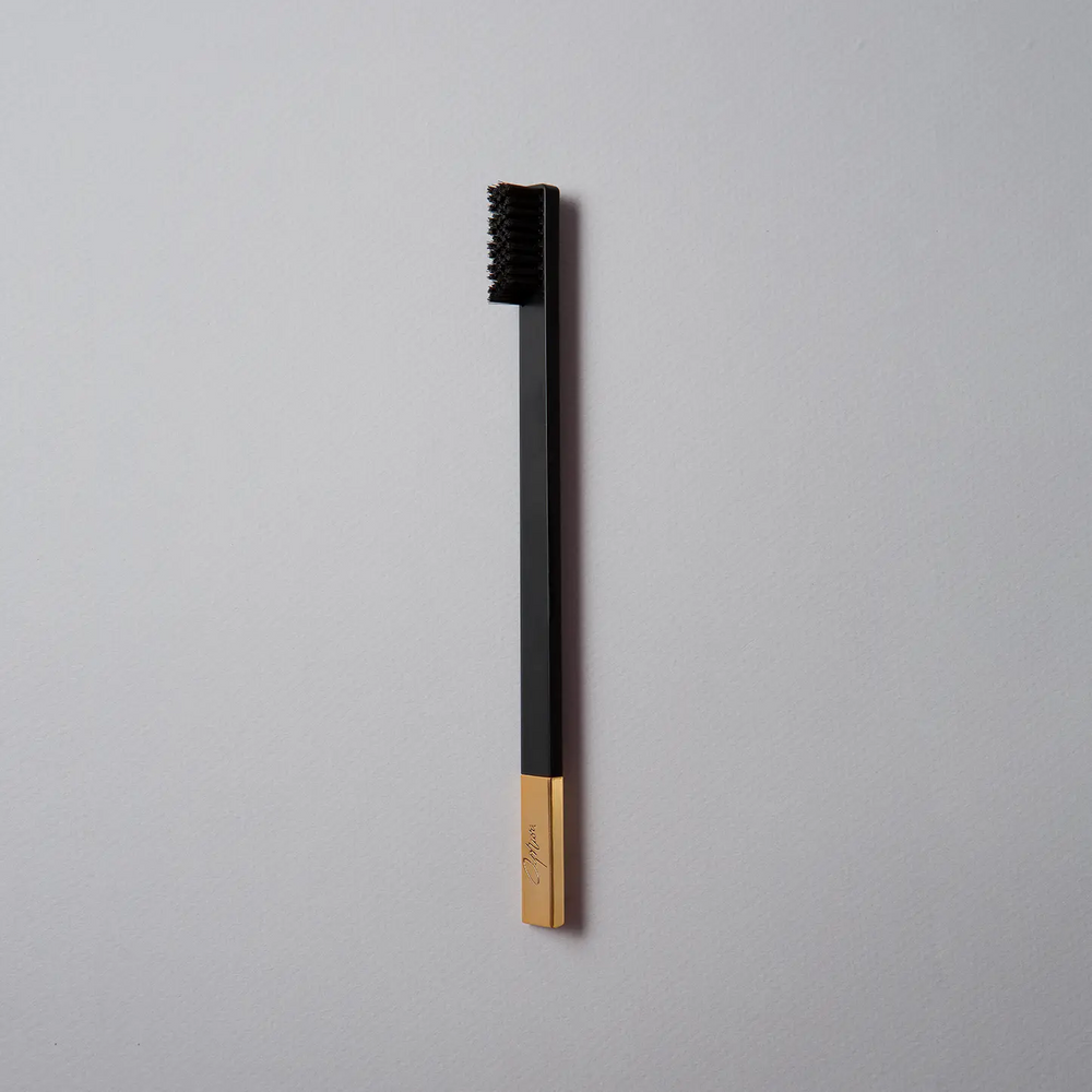 Black and gold toothbrush on a gray background