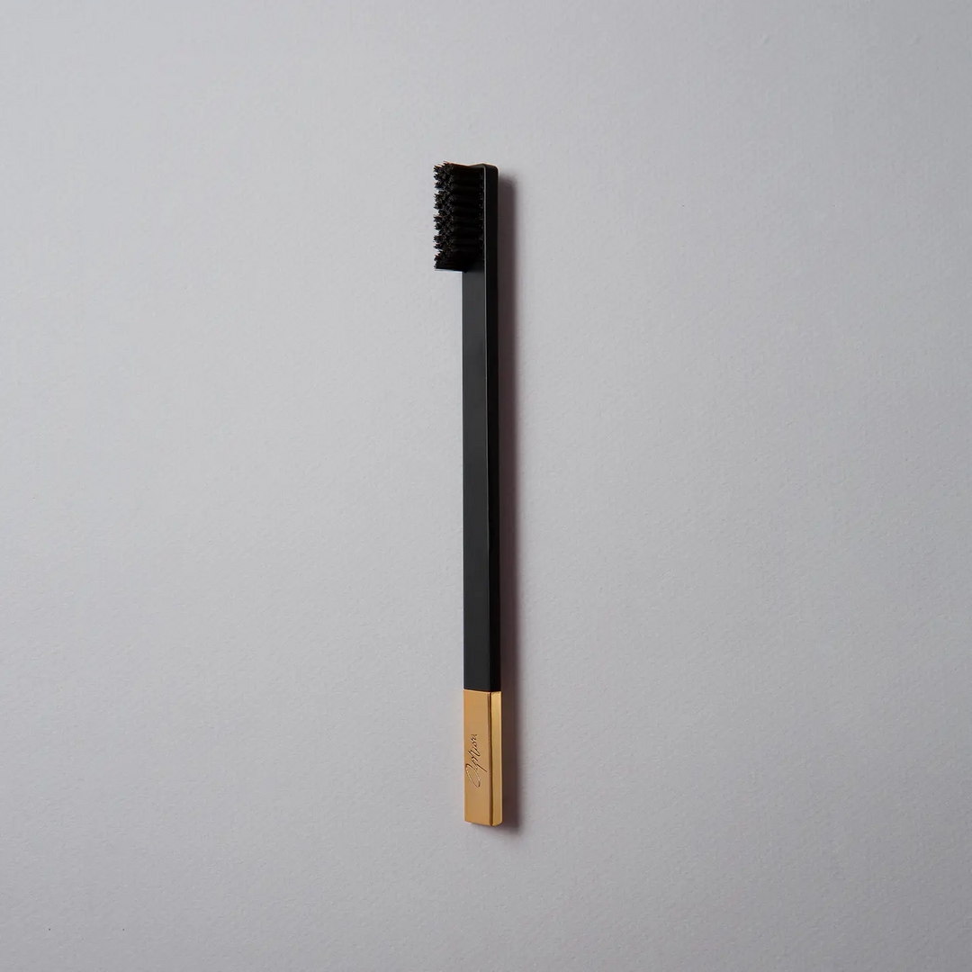 Black and gold toothbrush on a gray background