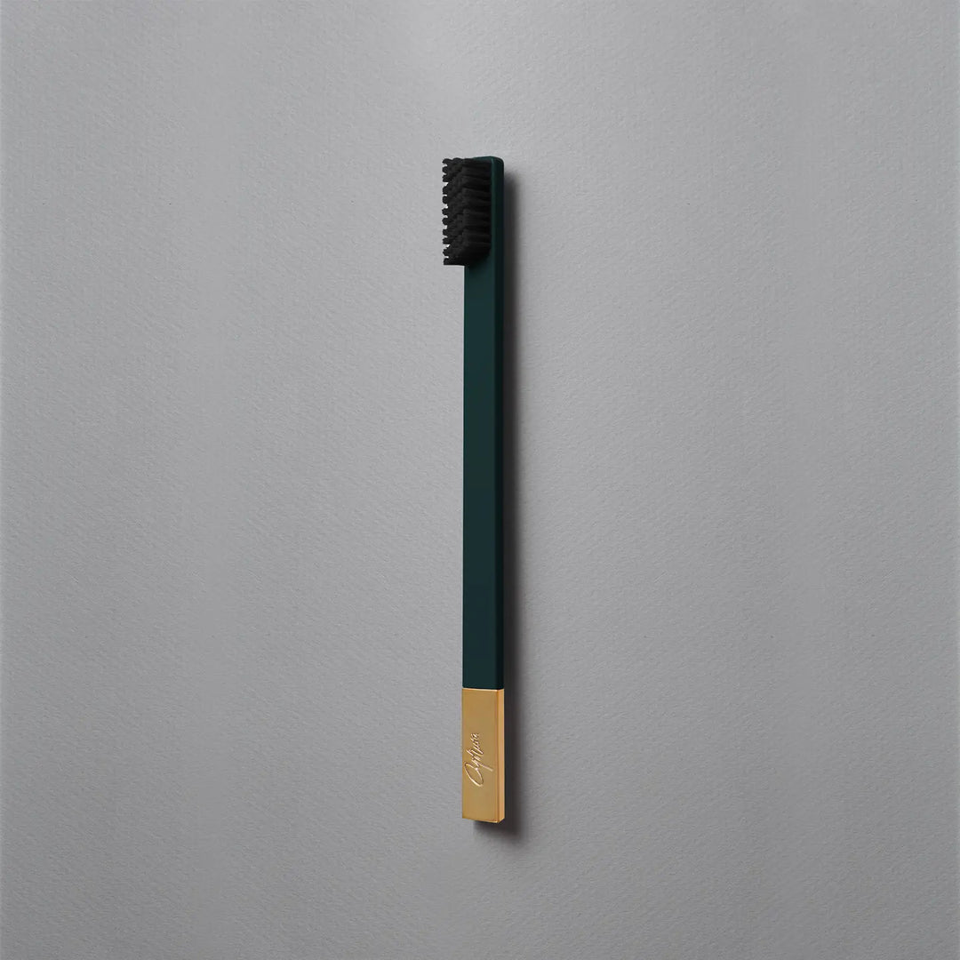 Green and gold toothbrush on a gray background