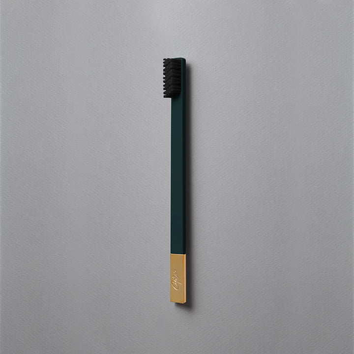 Green and gold toothbrush on a gray background