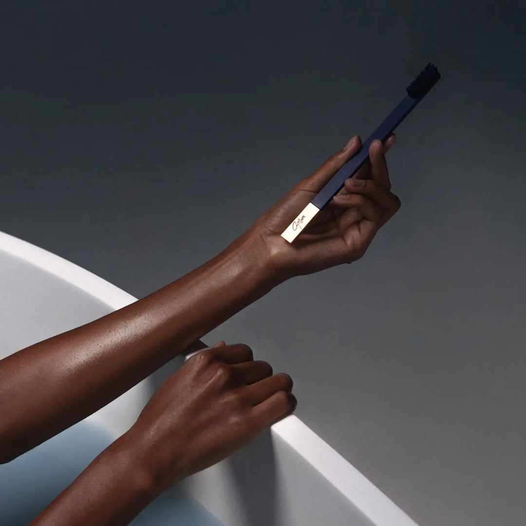 Person holding a black toothbrush with a white sink in the background