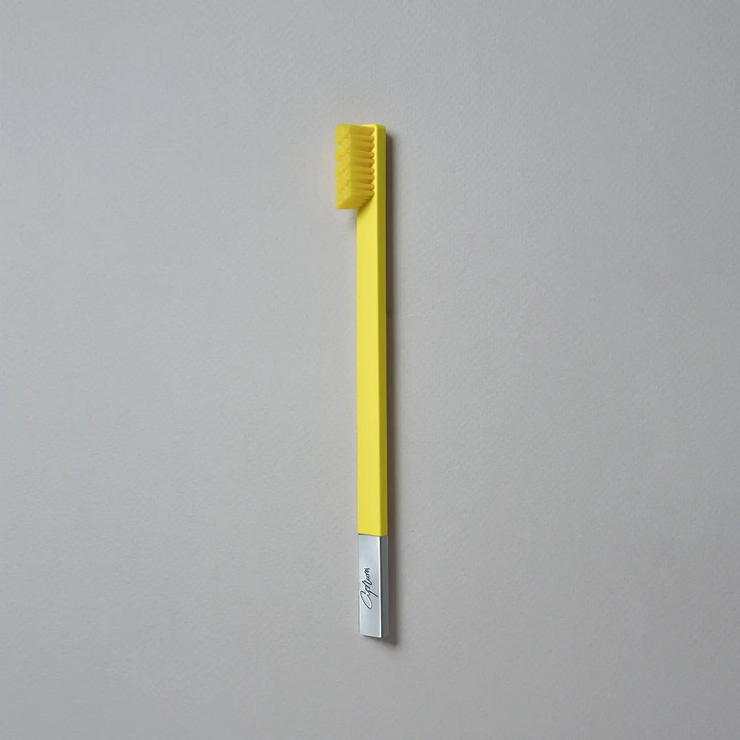 Yellow toothbrush with a silver handle on a gray background