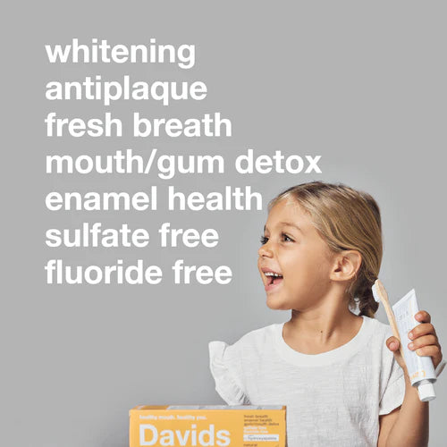 Child holding toothpaste and toothbrush with product features listed on a gray background