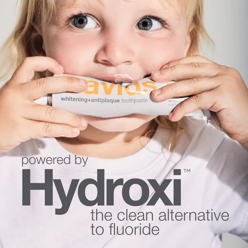 Child holding a tube of Avids toothpaste with Hydroxi branding.