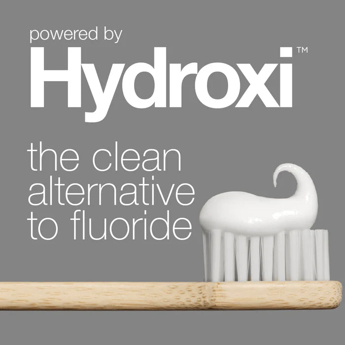 Bamboo toothbrush with a white brush head on a gray background, featuring the Hydroxi brand.
