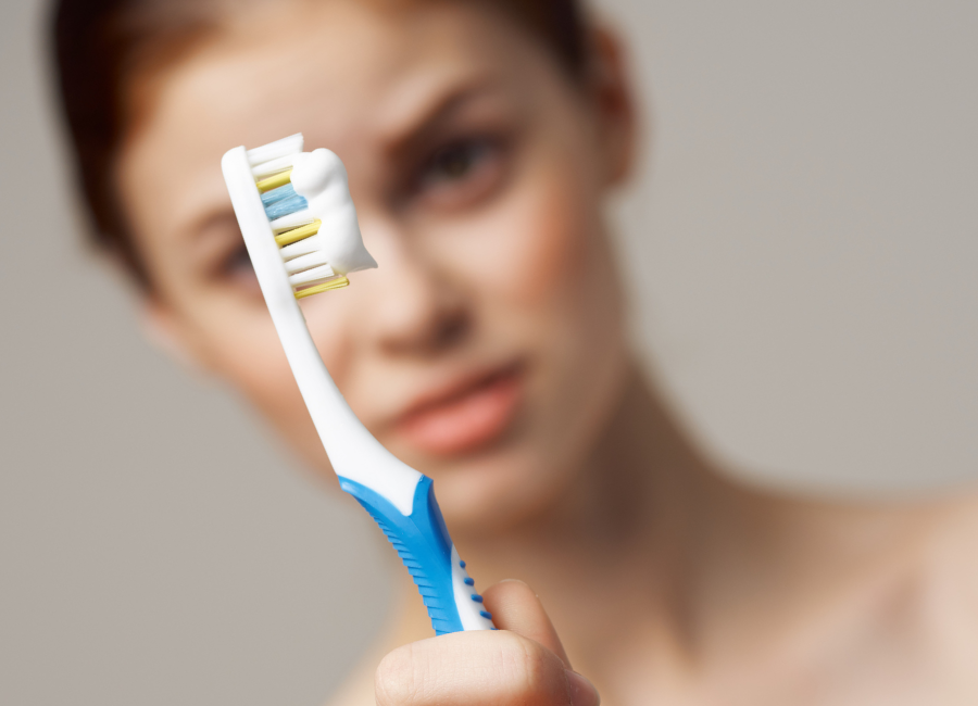 Woman holding toothbrush in front of face with toothpaste in focus