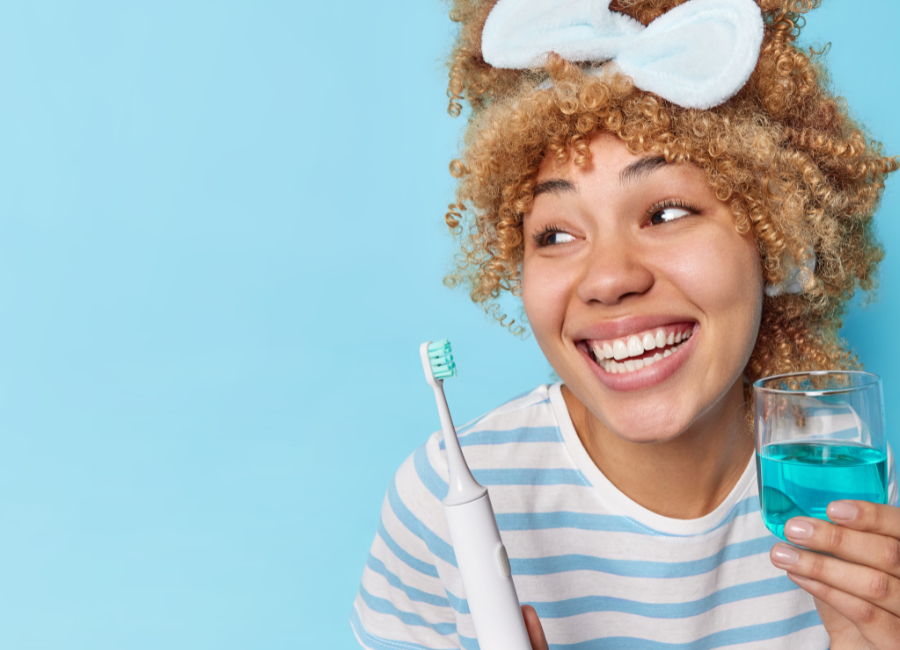 Bright smiling lady holding mouthwash and toothbrush