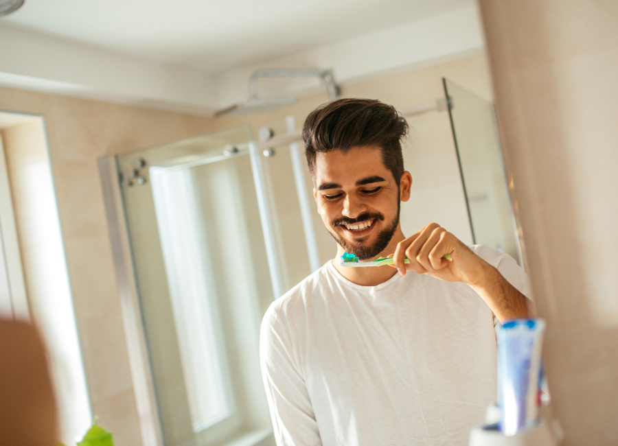 Man in white shirt brushing teeth in bathroom