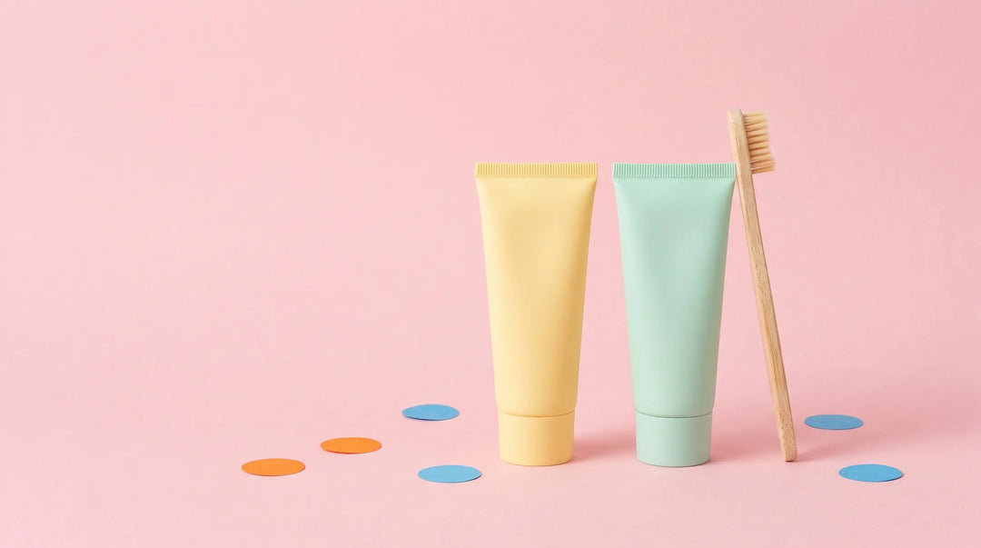 Pastel butter-yellow and mint-green kids toothpaste tubes on a pastel pink paper backdrop — Best Kids Toothpaste in Australia 2026.