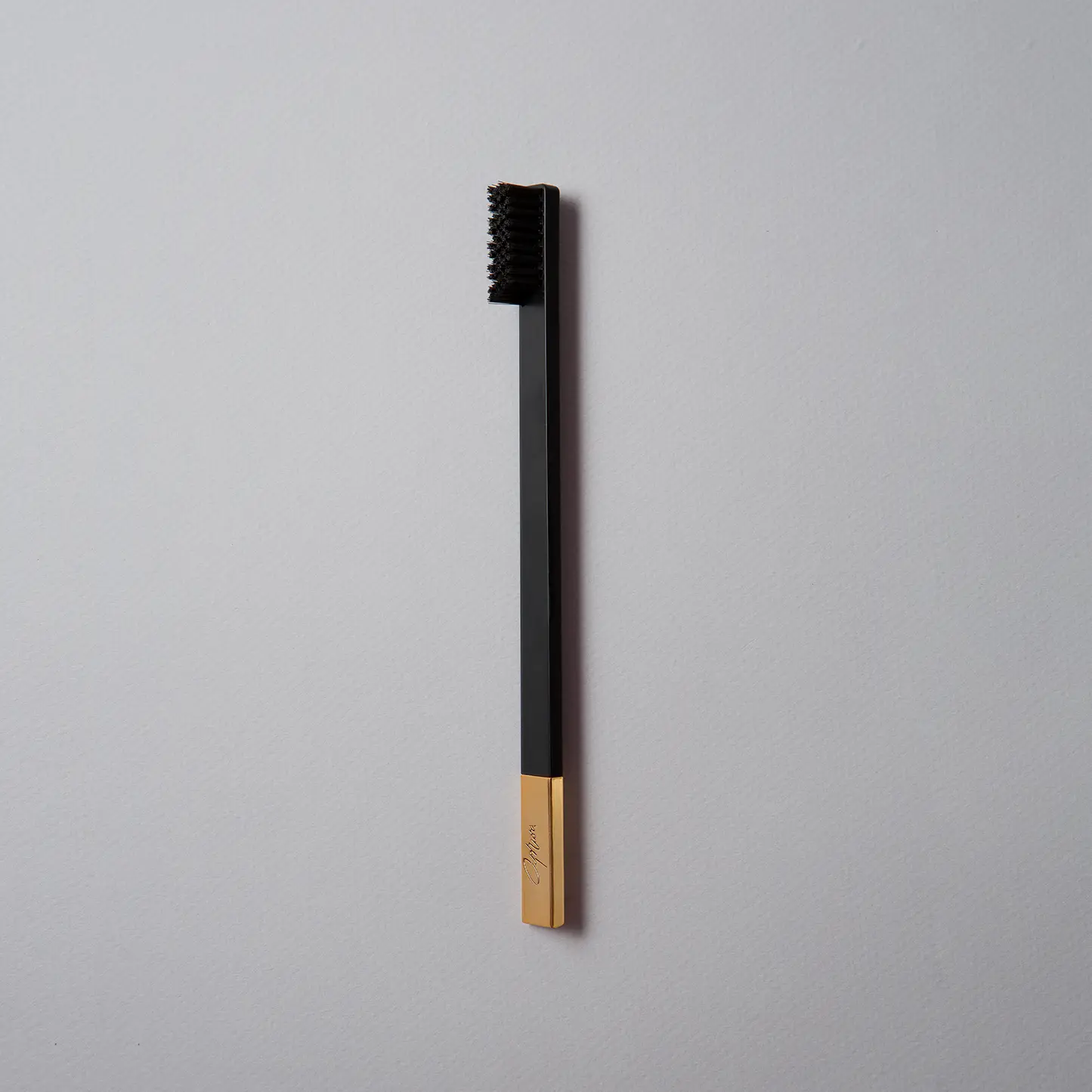 Black and gold toothbrush on a gray background