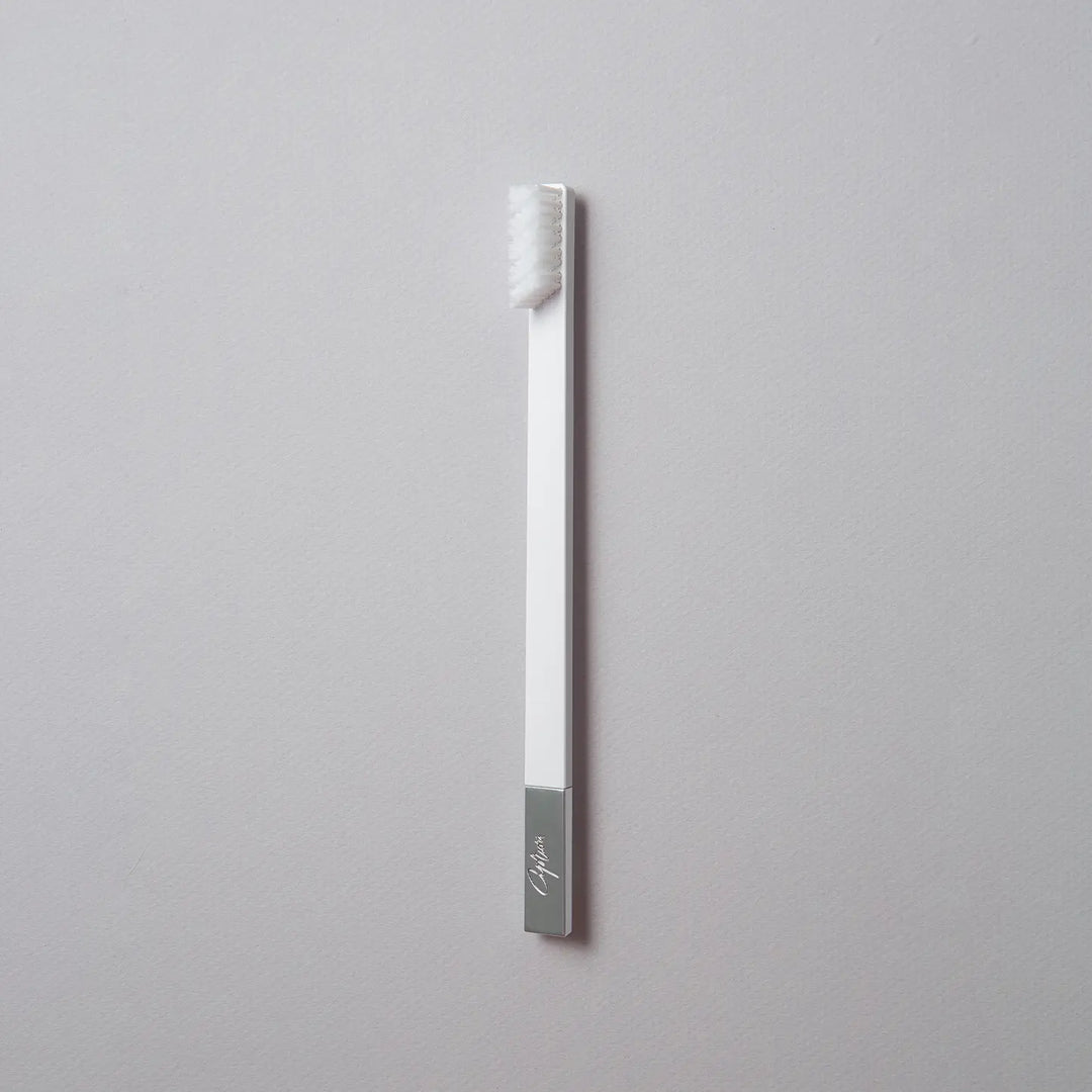 Silver toothbrush with a gray handle on a light gray background