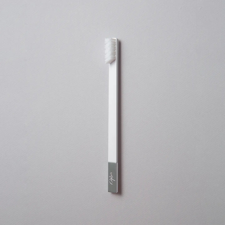 Silver toothbrush with a gray handle on a light gray background