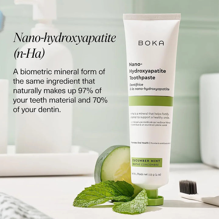 Boka Cucumber Mint toothpaste standing on a bathroom bench with a cucumber slice, mint sprig and toothbrush