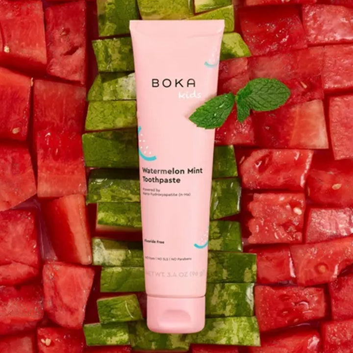 Boka Kids Watermelon Mint Toothpaste tube surrounded by watermelon pieces on a green background