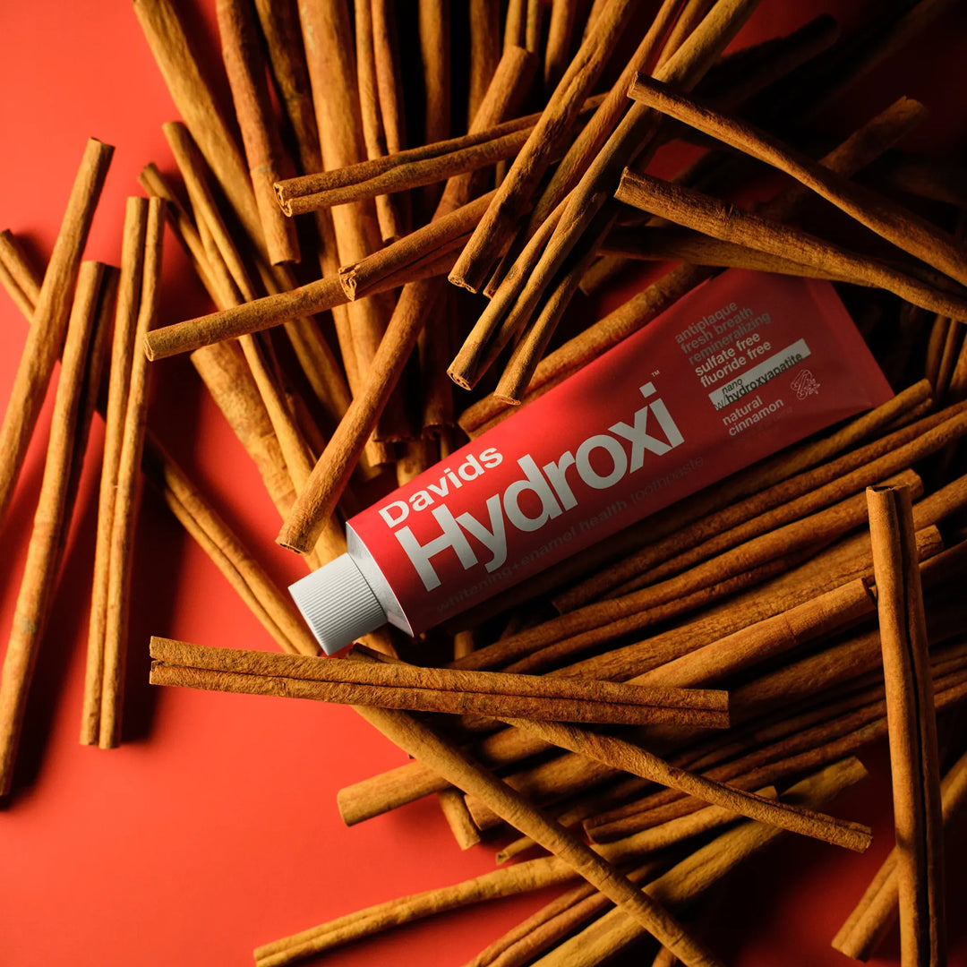 Davids Hydroxi cinnamon nano-hydroxyapatite toothpaste tube resting on a bed of cinnamon sticks