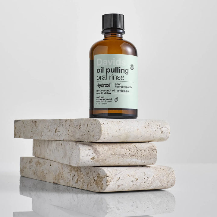 Davids oil pulling coconut oil oral rinse amber bottle styled on natural stone tiles