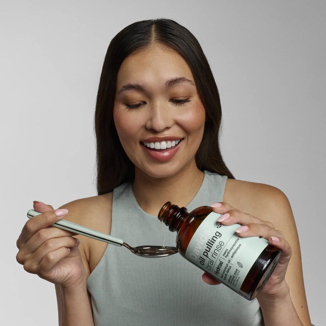 Pouring Davids oil pulling oral rinse onto a spoon for a coconut-oil mouth rinse