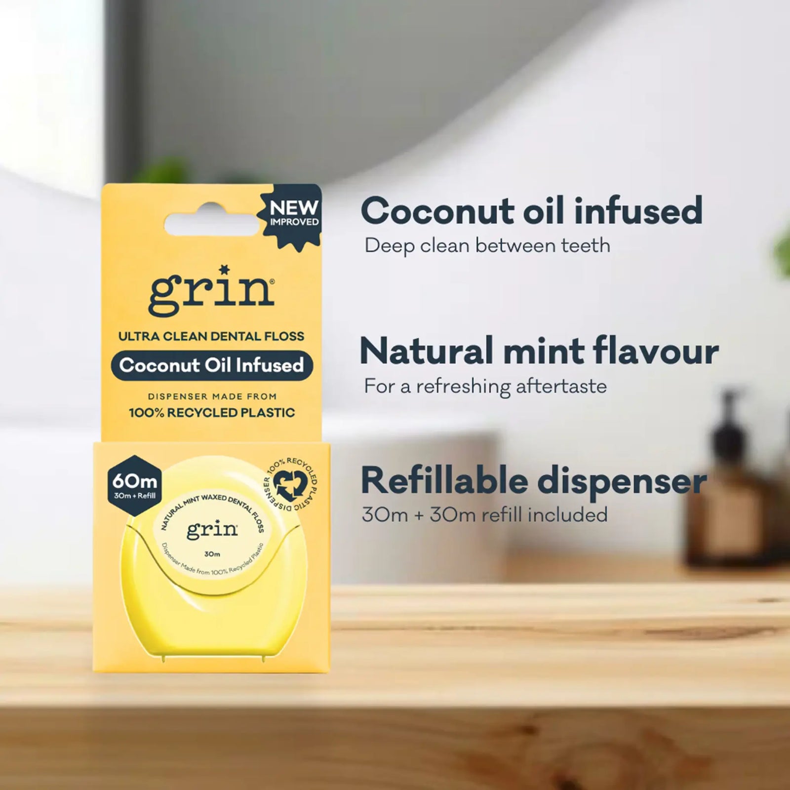 Packaging of grin coconut oil infused dental floss on a wooden surface with a blurred bathroom background.