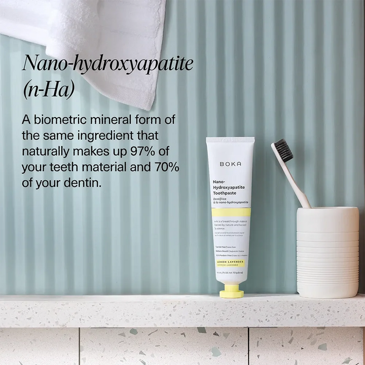 Boka Lemon Lavender toothpaste on a bathroom shelf with a toothbrush in a ceramic holder against a pale blue fluted wall