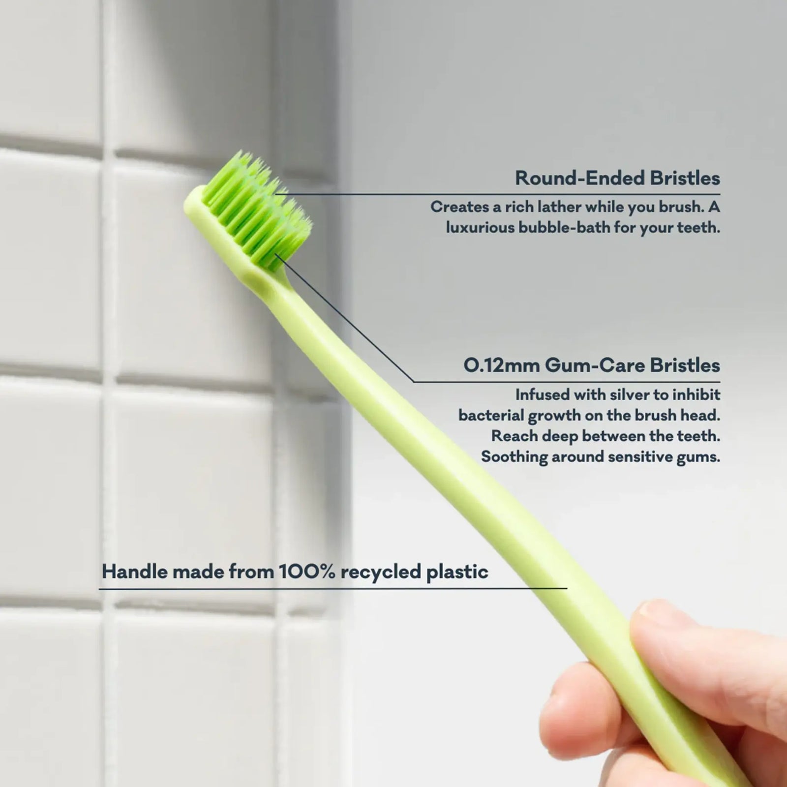 Green toothbrush with text detailing features against a tiled wall background
