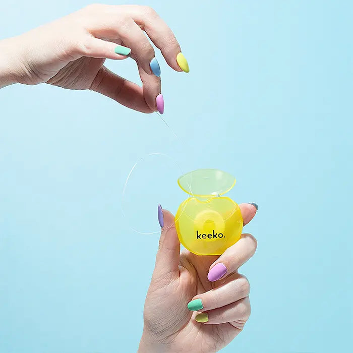 Hand holding a yellow 'keeko' product against a light blue background