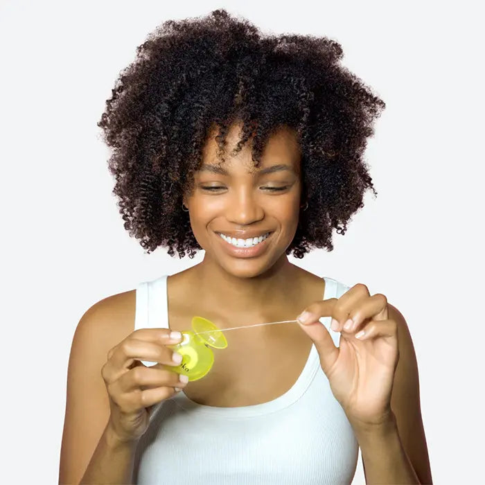 Woman holding a yellow dental floss against a plain background
