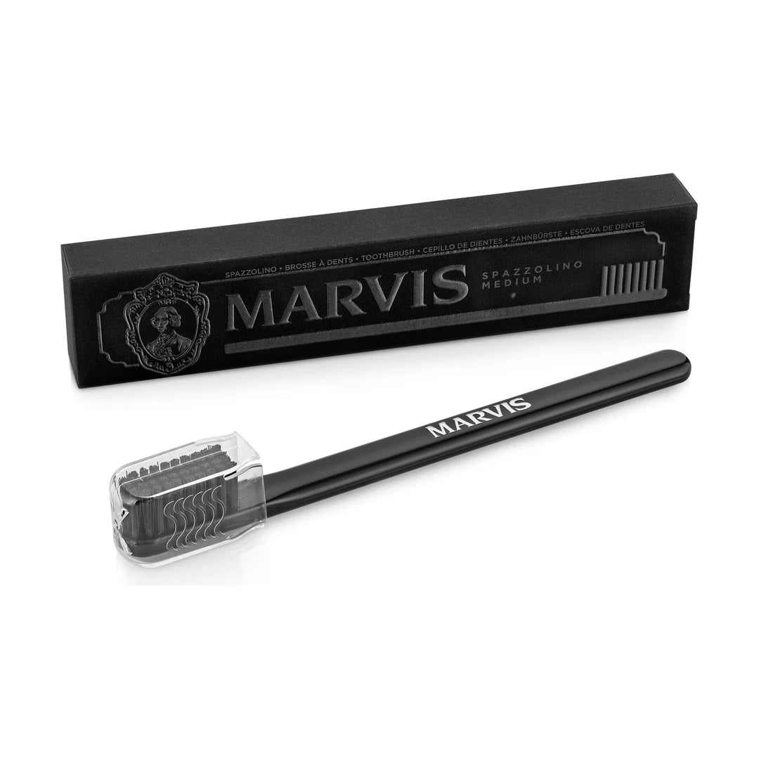 Black Marvis toothbrush with black medium bristles under a clear head cap, set before its black box marked SPAZZOLINO MEDIUM
