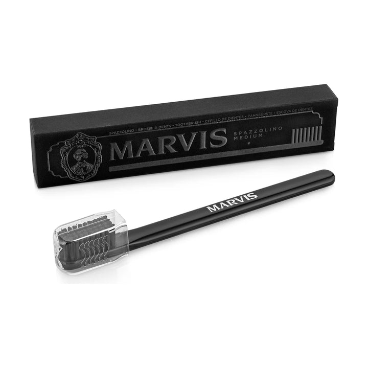 Black Marvis toothbrush with black medium bristles under a clear head cap, set before its black box marked SPAZZOLINO MEDIUM