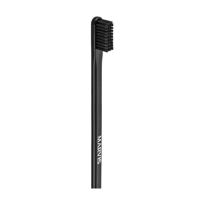 Uncapped black Marvis toothbrush standing vertically, head and black bristles uppermost, MARVIS in white letters along the handle