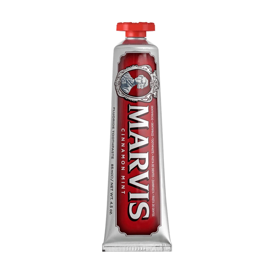 Upright Marvis Cinnamon Mint fluoride toothpaste tube with a red cap on top, a deep red label on silver and an ornate cameo frame