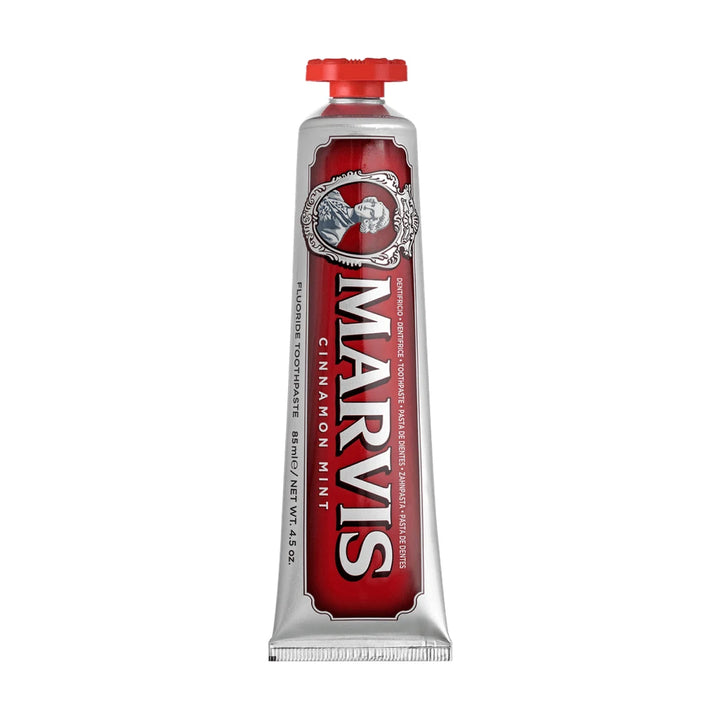 Upright Marvis Cinnamon Mint fluoride toothpaste tube with a red cap on top, a deep red label on silver and an ornate cameo frame
