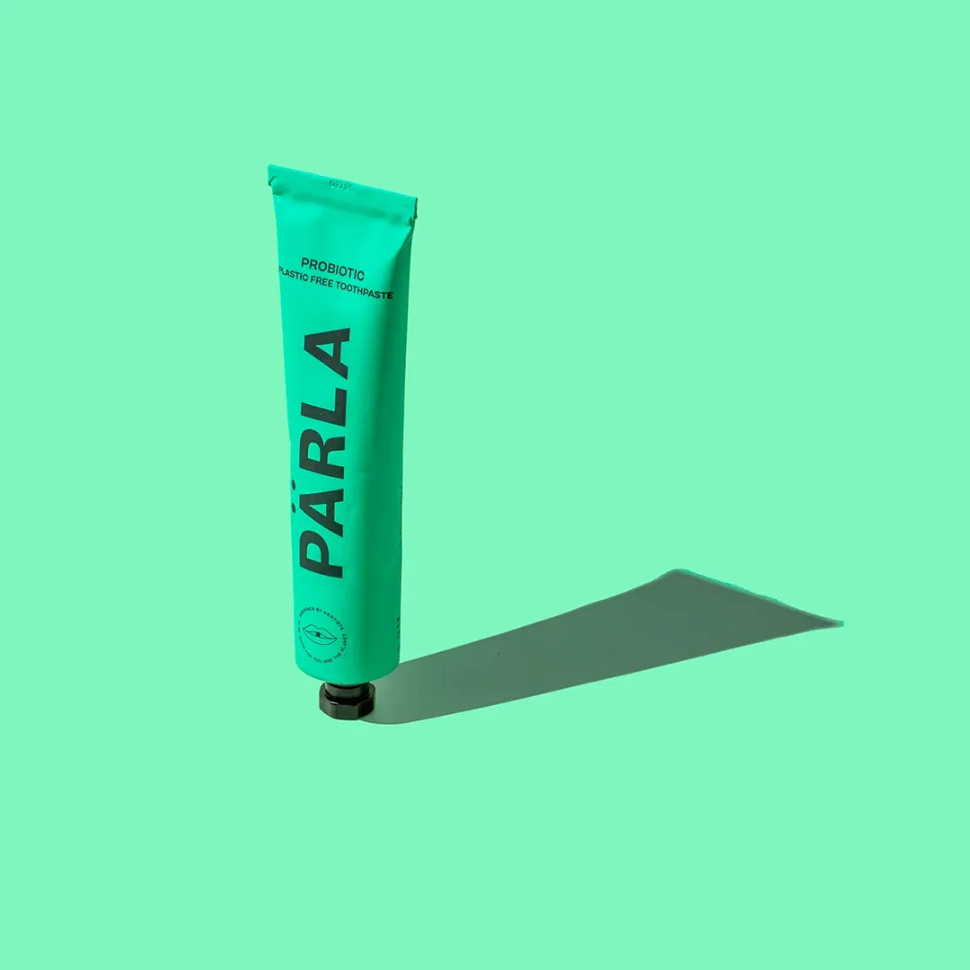 PÄRLA Bio Balance plastic free toothpaste tube standing upright with a long shadow on mint green