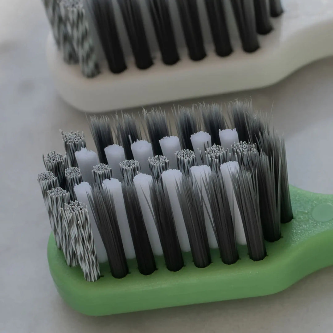 Close-up of a brush with black and white bristles on a green handle.